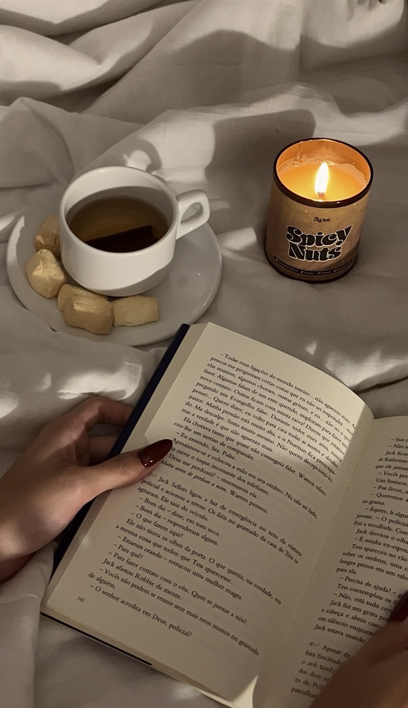 Vela Spicy Nuts acesa ao lado de um livro e um chá